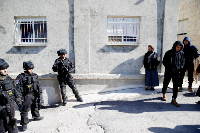 Israeli policemen stand in Jabel Mukaber on Monday next to Palestinians near the home of the Palestinian attacker who rammed his truck into a group of Israeli soldiers on Sunday in occupied Jerusalem. — Reuters