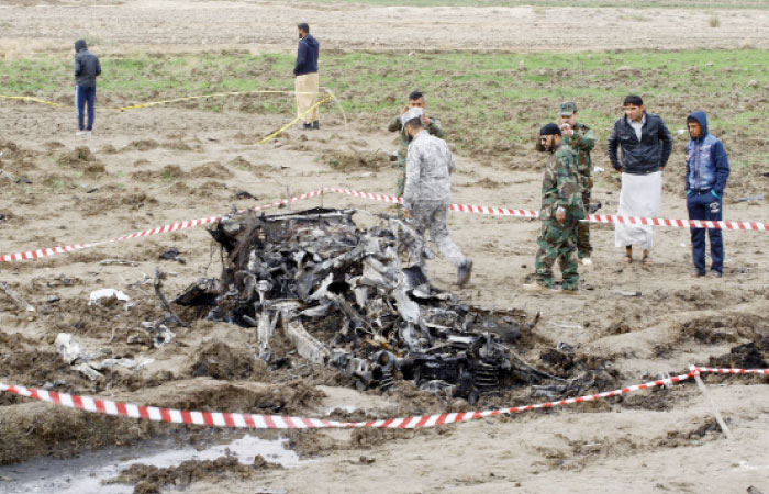 People gather as Iraqi security forces investigate the site of a suicide attack near the city of Najaf, Iraq, Sunday. — AP