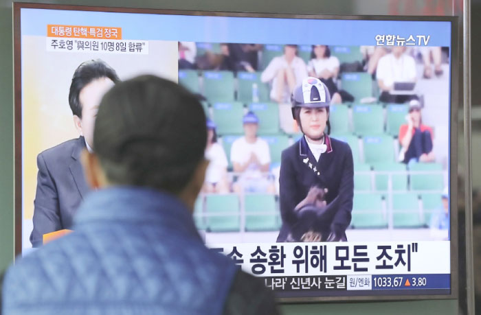 A man watches a TV screen showing the news program about Chung Yoo-ra, the daughter of the Choi Soon-sil who the confidante of disgraced President Park Geun-hye, at the Seoul Railway Station in Seoul, South Korea, on Monday. — AP