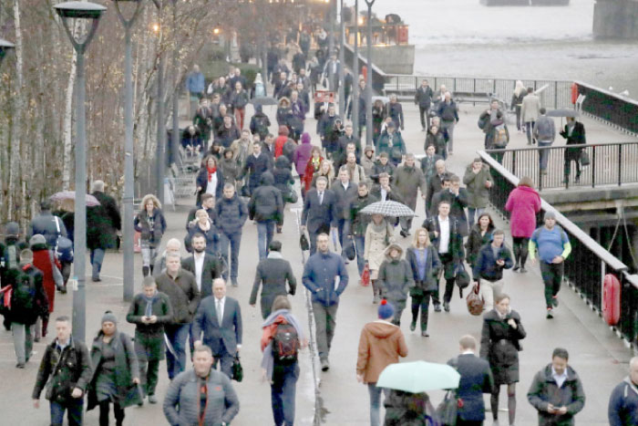 During the morning rush hour, people walk on the south side of the Rives Thames in London Bridge on Monday. — AP