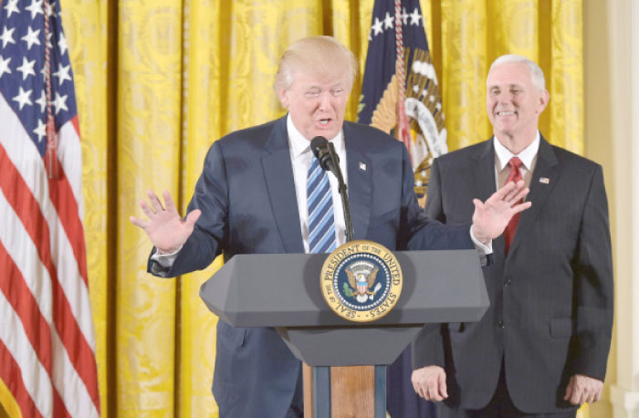 US President Donald Trump speaks, as Vice President Mike Pence watches, before the swearing in of the White House senior staff at the White House in Washington, D.C., on Friday. — AFP