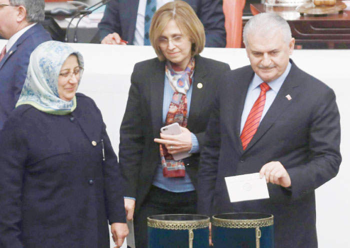 Turkish Prime Minister Binali Yildirim (C) casts his ballot during the parliamentary session for the debates on a bill to change the Turkish constitution at the Turkish Grand National Assembly (TBMM) in Ankara on Tuesday. — AFP