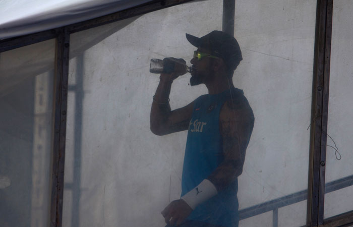 Indian captain Virat Kohli, drinks water as he arrives for a training session. — AP