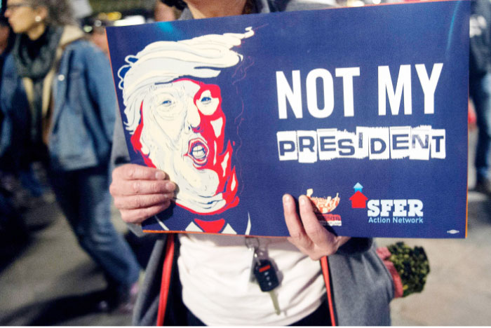 A demonstrator holds an anti-Trump sign during during a President’s Day protest march in Denver, Colorado. The demonstration was one of many “Not My President’s Day” anti-Trump marches held throughout the US — AFP