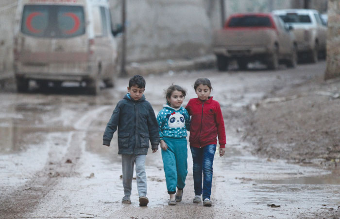 Children walk near a parked ambulance in Al-Rai town, northern Aleppo province.