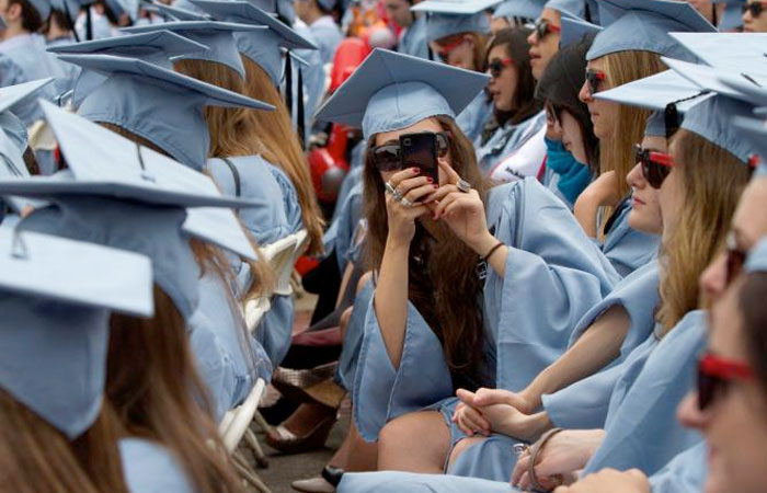 A graduate from Columbia University's Barnard College uses her a mobile phone to take a photo during the university's commencement ceremony in New York. — Reuters