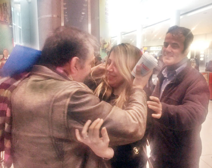 Fariba Tajrostami, center, of Iran, is embraced by her brothers Joseph, left, and Eddie, right, Sunday. — AP
