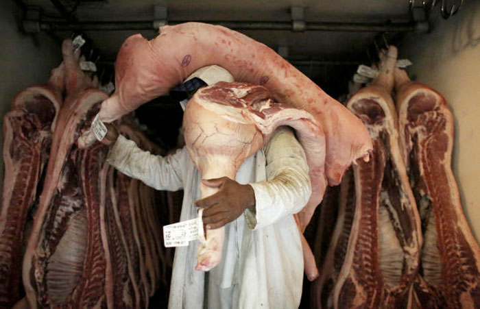 An employee carries pieces of meat at a butchery in Sao Paulo, Brazil. — Reuters