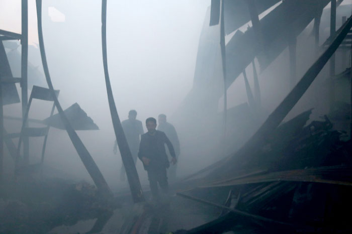 Syrian volunteers, known as the White Helmets, walk amid debris as they extinguish fire reportedly caused by air strikes in the rebel-controlled town of Hamouria, in the eastern Ghouta region on the outskirts of the capital Damascus. — AFP
