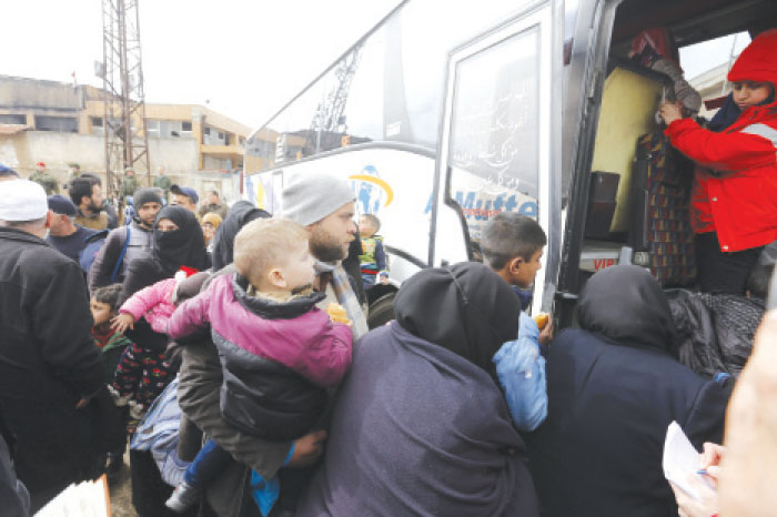 Opposition fighters and their families getting in a bus, following their evacuation from the rebel-held Al-Waer neighborhood in the central city of Homs on Saturday, during the first phase of the Russian-supervised deal to complete the evacuation of fighters and civilians. — AFP