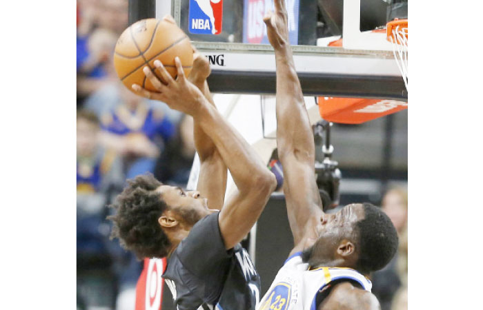 Minnesota Timberwolves’ Andrew Wiggins (L) shoots over Golden State Warriors’ Draymond Green during their NBA game in Minneapolis Friday. — AP
