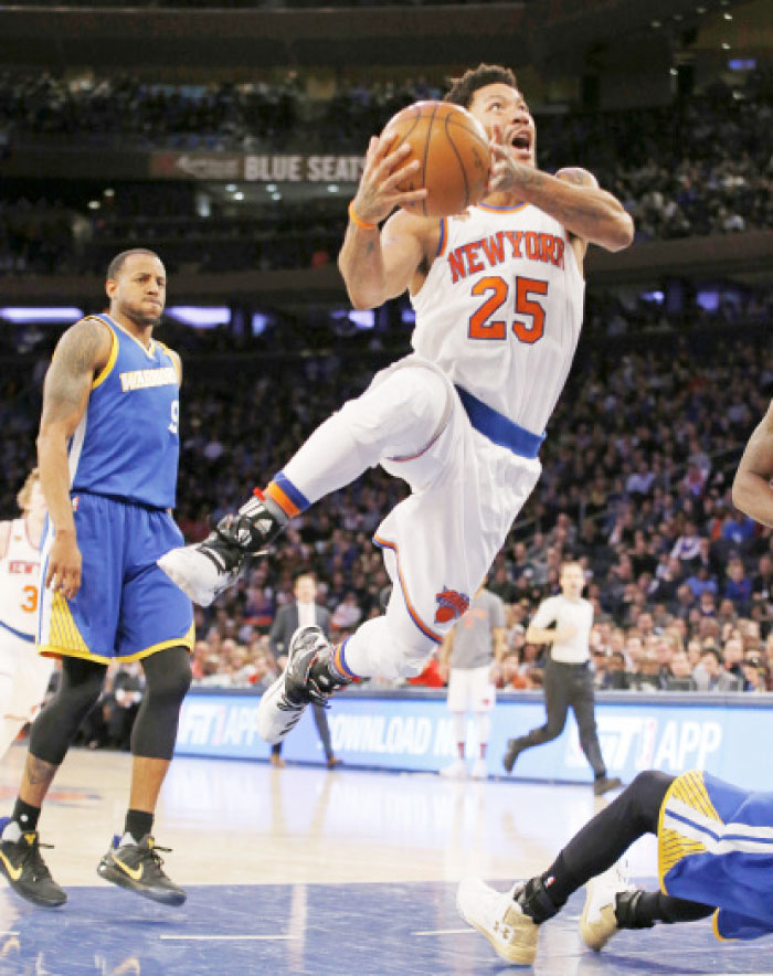 New York Knicks guard Derrick Rose (25) goes for a layup and knocks Golden State Warriors guard Stephen Curry to the floor as Warriors forward Andre Iguodala (9) reacts in the second half of an NBA basketball game at Madison Square Garden in New York, on Sunday. — AP