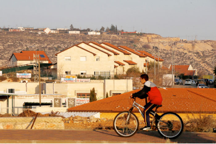 A boy rides his bicycle past houses in the Israeli settlements of Ofra, in the occupied West Bank, in this file photo. — Reuters