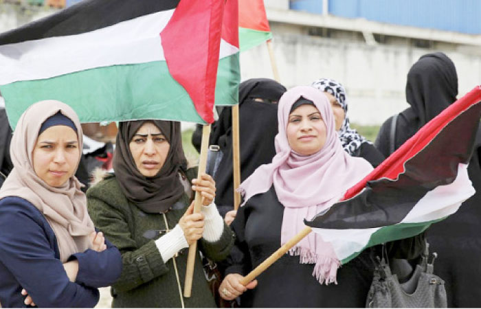Women wave their national flags during a rally marking the 41st anniversary of Land Day, on the Palestinian side of the Beit Hanoun border crossing between Israel and the Gaza Strip in this file photo. — AP