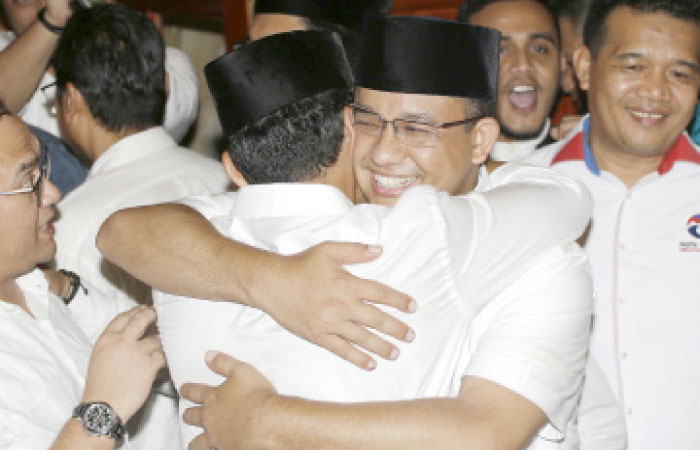 Gubernatorial candidate Anies Baswedan, center right, hugs his running mate Sandiaga Uno during a press conference in Jakarta, Indonesia, on Wednesday. — AP