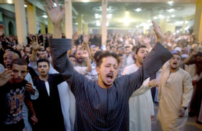 Coptic Christians shout slogans during a funeral service for victims of a bus attack, at Abu Garnous Cathedral in Minya, Egypt. — AP