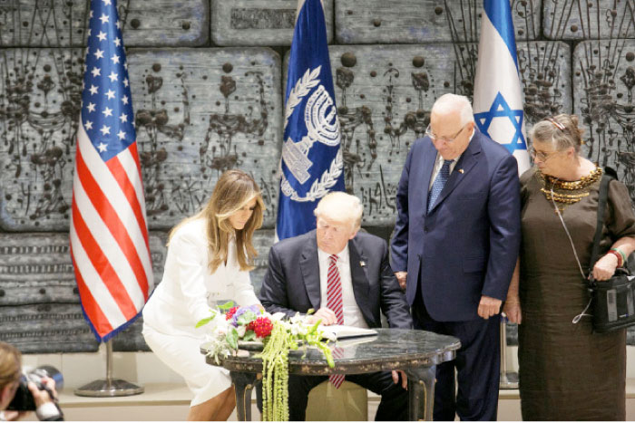 US President Donald Trump (2ndL) looks at his wife Melania signing a guest book as Israeli President Reuven Rivlin (3rd L) and his wife Nechama (R) stand nearby at Rivlin’s residence in occupied Jerusalem on Monday. — Reuters