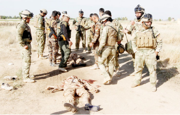 Kurdish peshmerga forces stand near the bodies of suicide bombers of Daesh, in the city of Kirkuk, Iraq. - Reuters