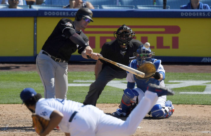 Miami Marlins first baseman Justin Bour, left, hits a solo home run as Los Angeles Dodgers relief pitcher Kenley Jansen, below, watches along with catcher Yasmani Grandal, right, and home plate umpire Paul Nauert during the ninth inning of a baseball game, Sunday in Los Angeles. — AP