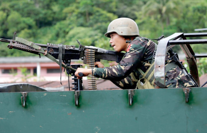 A government soldier holds a weapon aboard an armored fighting vehicle (AFV) as soldiers advance their position in Marawi City, Philippines, on Sunday. — Reuters