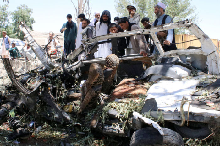 Afghan men inspect a car damaged in a suicide car bomb attack in Khost province, Afghanistan, on Saturday. — Reuters