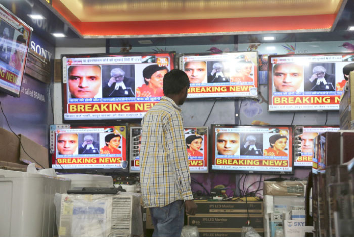 An Indian boy watches as television channels show news about International Court of Justice hearing the case of Indian naval officer Kulbhushan Jadhav at a shop in Jammu, India, on Monday. — AP