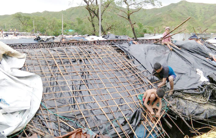 Rohingya refugee children fix the damaged roof of a hut in a makeshift camp in Bangladesh’s Cox’s Bazar district on Tuesday after Cyclone Mora made landfall in the region. — AFP