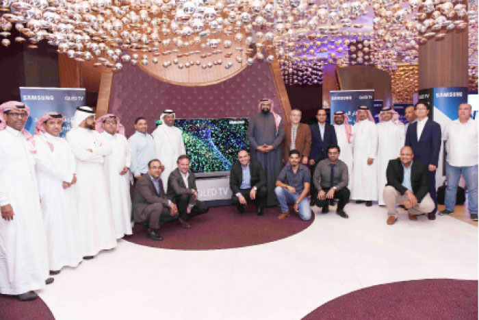 Members of the Saudi media with some Samsung executives pose beside Samsung QLED TV at the launch