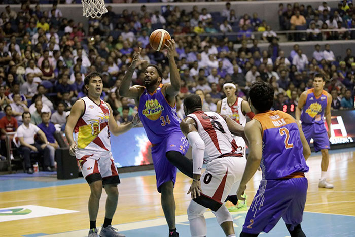 TNT's Joshua Smith powers his way to the basket as SMB's Charles Rhodes (0) and Yancy de Ocampo (left) look on in Game 1 of the PBA Commissioner's Cup Finals at the Smart-Araneta Coliseum on Wednesday night.