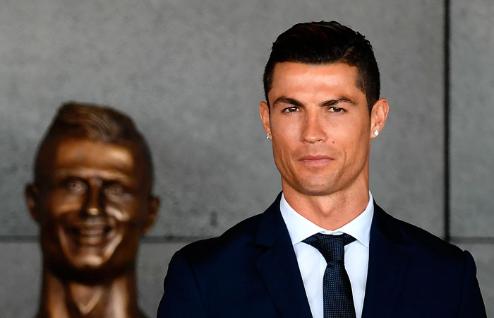 This file photo shows Portuguese footballer Cristiano Ronaldo standing beside a bust presented during a ceremony where Madeira's airport in Funchal is to be renamed after Cristiano Ronaldo, on Madeira island. State prosecutors have filed a complaint on Tuesday against the Portuguese star, who they accuse of taking advantage of a corporate structure to defraud the Spanish Treasury of 14.7 million euros. — AFP