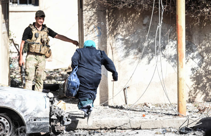 An Iraqi woman runs toward a Rapid Response forces member in Mosul’s western Al-Shifa district as they battle against Daesh group. — AFP