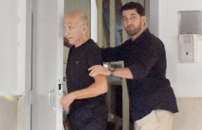 Former Israeli prime minister Ehud Olmert walks out of the prison door on Sunday at Maasiyahu prison near Ramle, Israel, as he is released from prison after a parole board decided to cut his sentence by a third. — Reuters
