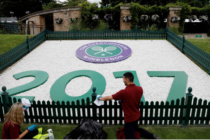 Staff clean at Wimbledon tennis club in southwest London Saturday. — AFP