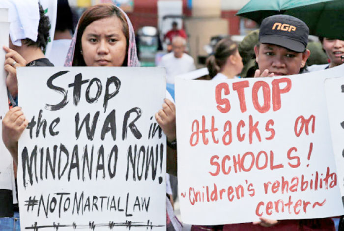 Activists hold placards calling for peace in war-torn Marawi as they join other protesters on President Rodrigo Duterte’s first year in office during a rally outside the presidential palace in Metro Manila in this June 30 2017 file photo. — Reuters